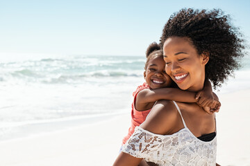 Happy mother giving daughter piggyback ride at beach