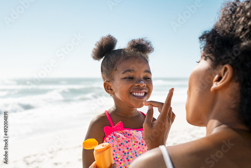 Lovely black mother applying sunscreen on cute little black girl photo