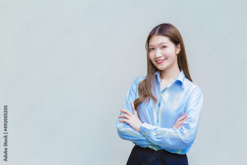 Professional Asian working woman who has long hair wears blue shirt while she arm crossing and smiling happily on white background. Professional Asian working woman who has long hair wears blue shirt while she arm crossing and smiling happily on white background.