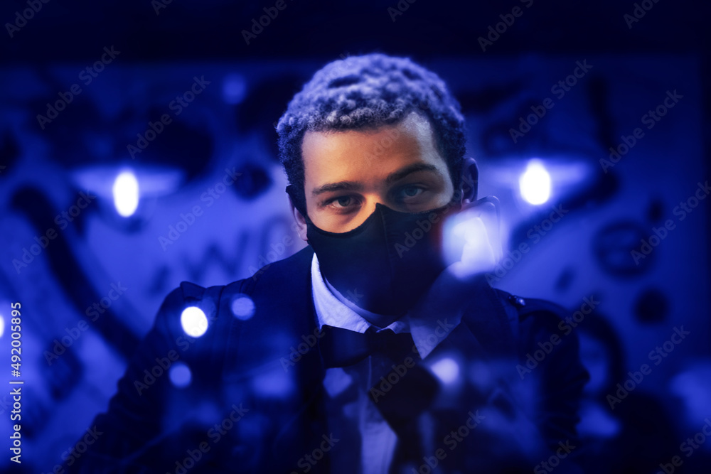 Portrait of young handsome African American man wearing protective face mask through the window of a street cafe or restaurant Portrait of young handsome African American man wearing protective face mask through the window of a street cafe or restaurant