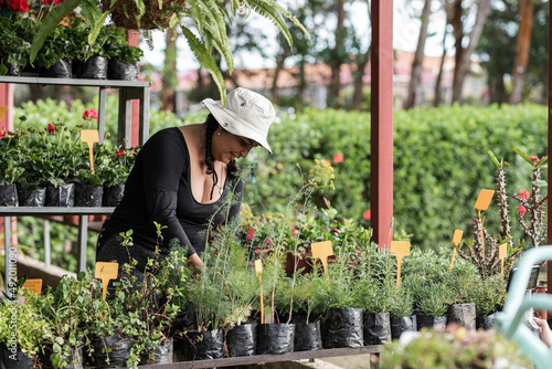 Obraz na plátne Short, heavy-set Latina woman working in her botanical garden with a hat on her head, very happy