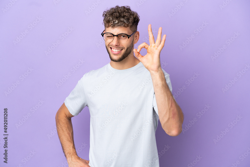 Fototapeta premium Delivery caucasian man isolated on purple background showing ok sign with fingers