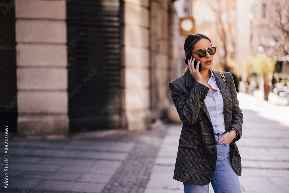 Fototapeta premium Well-dressed woman, spending time outside, using the phone.