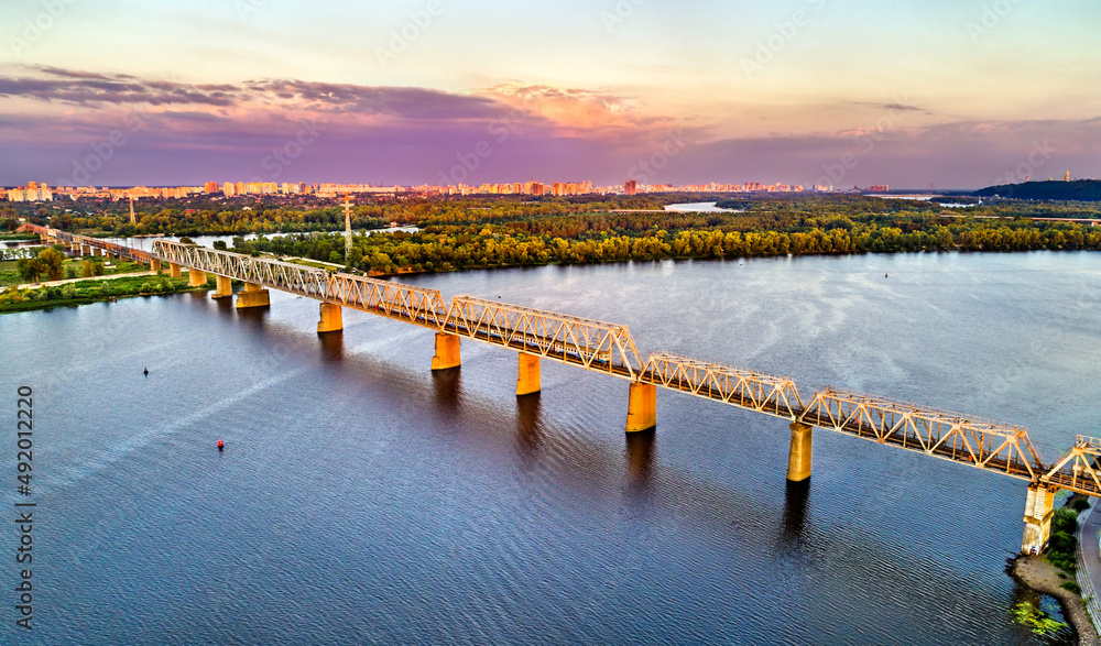 Obraz premium Kiev Urban Electric Train on the Petrovsky Railway Bridge across the Dnieper in Ukraine. Peaceful Kyiv before the war with Russia