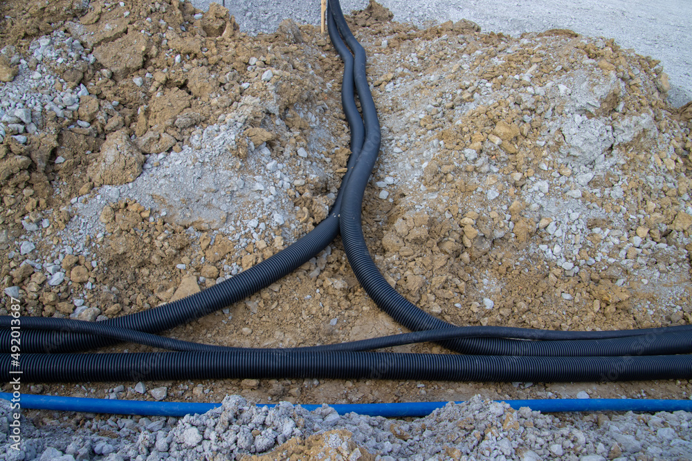 Black corrugated plastic drainage pipes laying in a ditch at a construction site