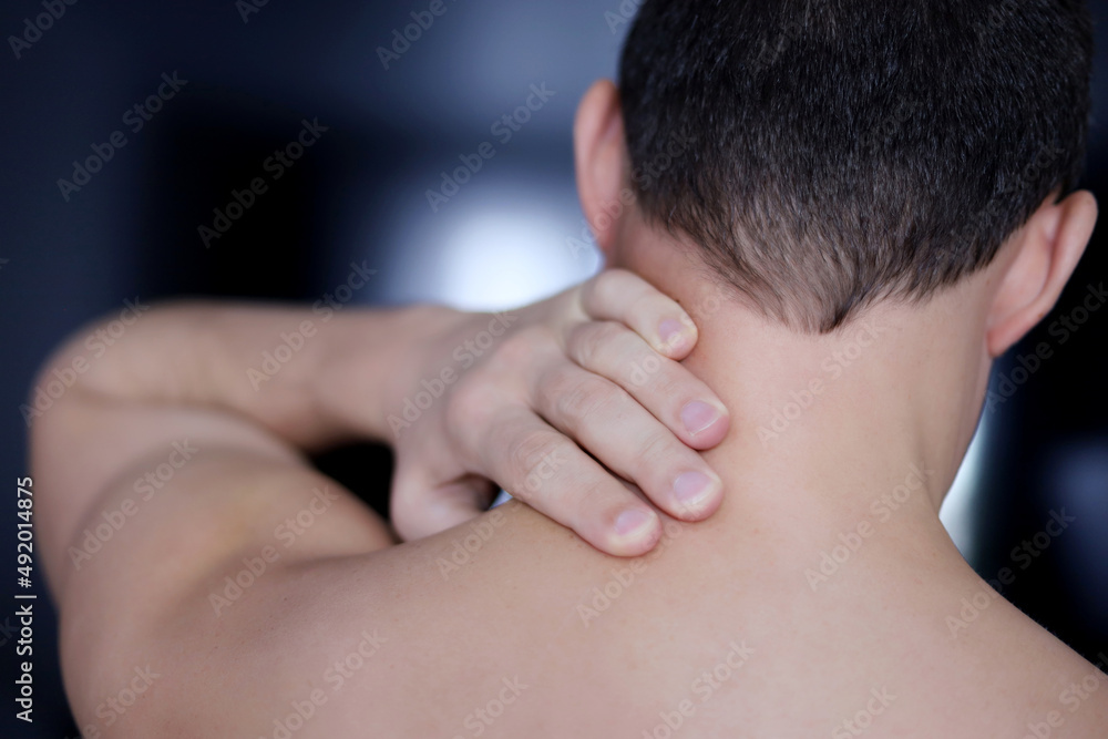 Shirtless man with neck pain. Symptom of cervical chondrosis, inflammation of the vertebra, back view