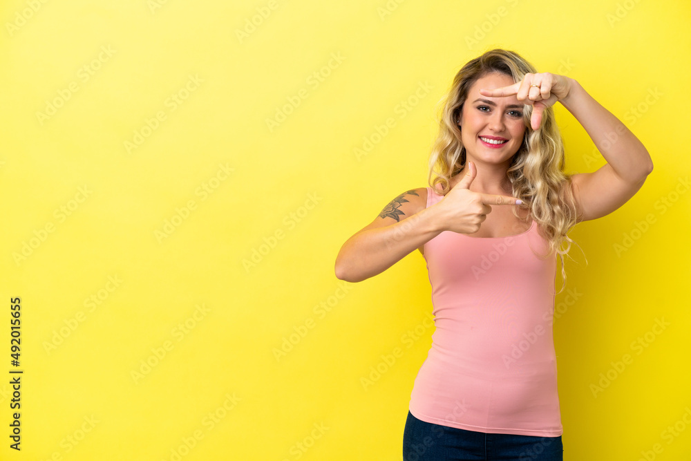Young Brazilian woman isolated on yellow background focusing face. Framing symbol Young Brazilian woman isolated on yellow background focusing face. Framing symbol