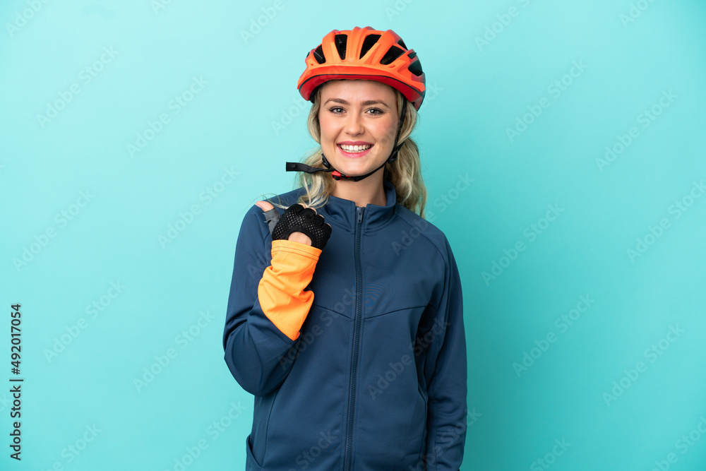 Young cyclist woman isolated on blue background pointing to the side to present a product Young cyclist woman isolated on blue background pointing to the side to present a product