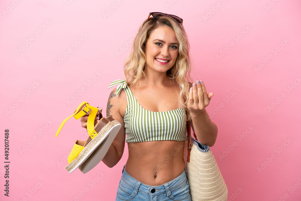 Young Brazilian woman in swimsuit in summer holidays isolated on pink background inviting to come with hand. Happy that you came Young Brazilian woman in swimsuit in summer holidays isolated on pink background inviting to come with hand. Happy that you came
