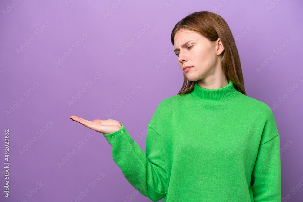 Young English woman isolated on purple background holding copyspace with doubts Young English woman isolated on purple background holding copyspace with doubts