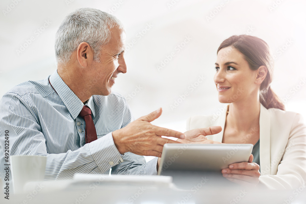 Explaining the finer points of business. Shot of two coworkers sitting at a table using a digital tablet. Explaining the finer points of business. Shot of two coworkers sitting at a table using a digital tablet.