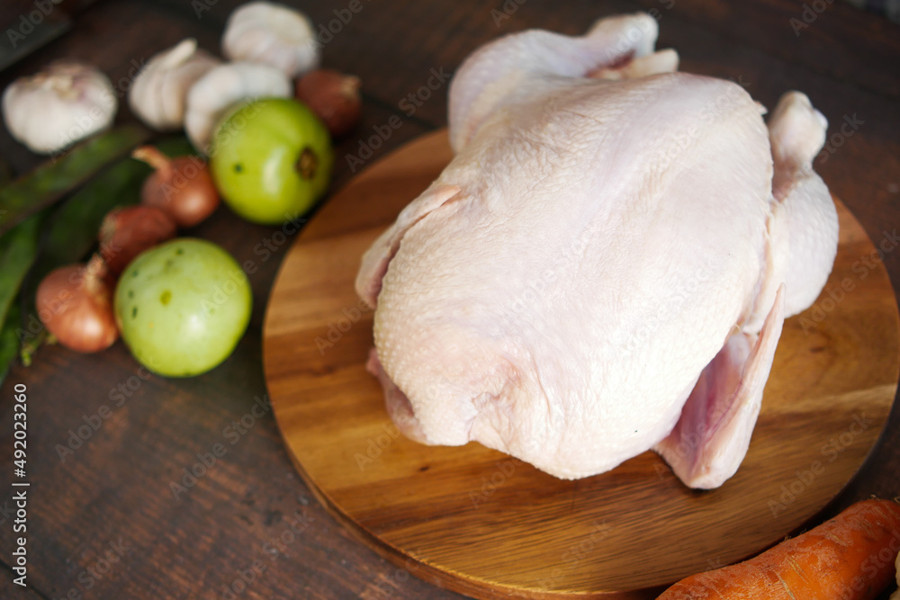 raw whole chicken and vegetables on tiles background raw whole chicken and vegetables on tiles background