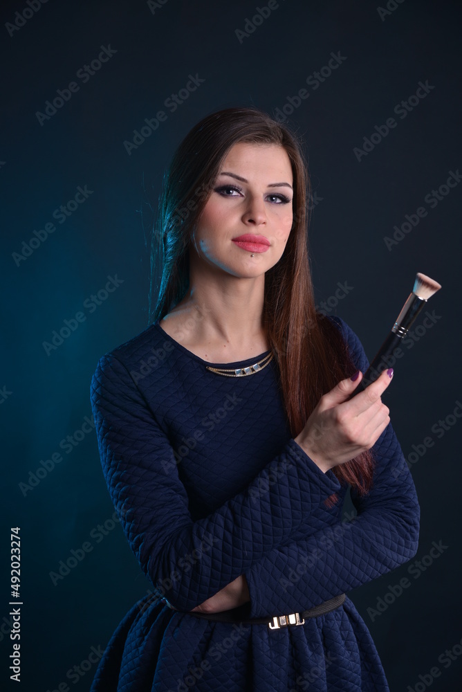 Obraz premium a series of photos of a young girl model - makeup artist with a brush for makeup in her hands, on a black isolated background
