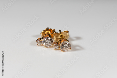 Yellow gold earrings with natural round diamonds on a white background © Anna