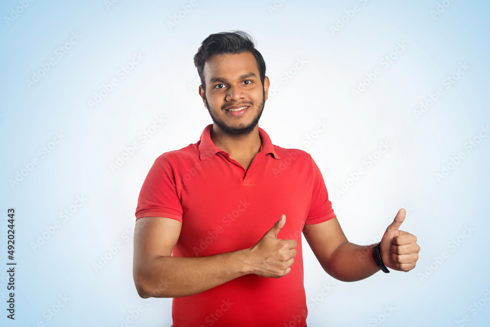 Young Indian Man Doing Happy Thumbs Up Gesture With Hand, Approving Expression Looking At The Camera Showing Success Young Indian Man Doing Happy Thumbs Up Gesture With Hand, Approving Expression Looking At The Camera Showing Success