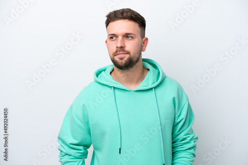 Young caucasian man isolated on white background having doubts while looking side © luismolinero