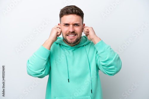 Young caucasian man isolated on white background frustrated and covering ears © luismolinero