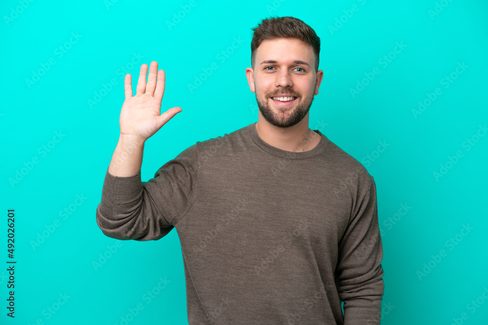 Young caucasian man isolated on blue background saluting with hand with happy expression Young caucasian man isolated on blue background saluting with hand with happy expression