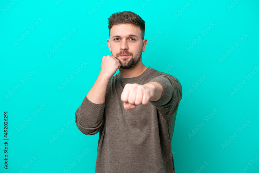 Young caucasian man isolated on blue background with fighting gesture Young caucasian man isolated on blue background with fighting gesture