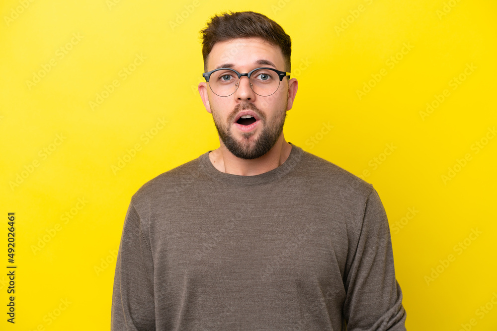 Young caucasian man isolated on yellow background With glasses and surprised expression Young caucasian man isolated on yellow background With glasses and surprised expression