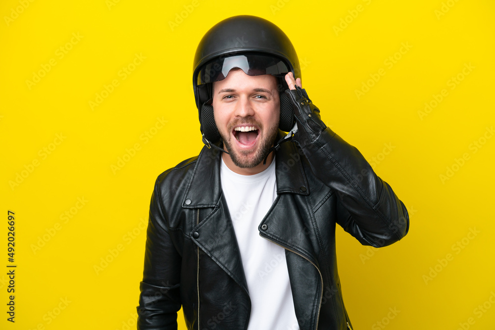 Young caucasian man with a motorcycle helmet isolated on yellow background with surprise and shocked facial expression Young caucasian man with a motorcycle helmet isolated on yellow background with surprise and shocked facial expression