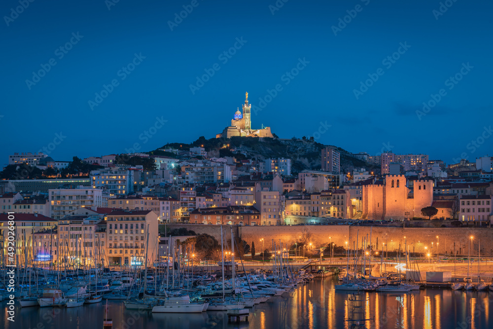 The Old Port and Basilica of Notre Dame de la Garde at dusk in Marseille, France