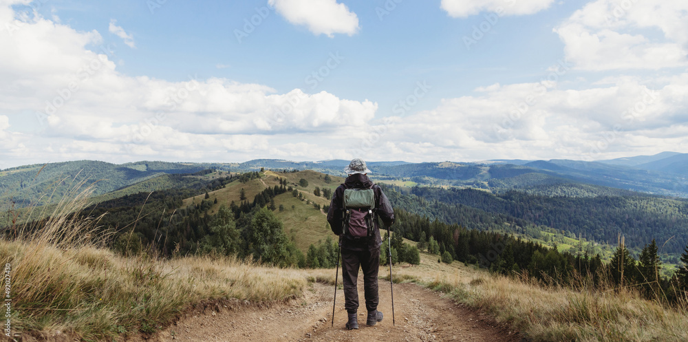 Hiker man with backpack and trekking sticks