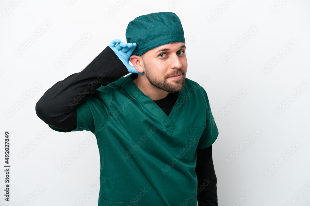 Surgeon in green uniform isolated on white background listening to something by putting hand on the ear Surgeon in green uniform isolated on white background listening to something by putting hand on the ear