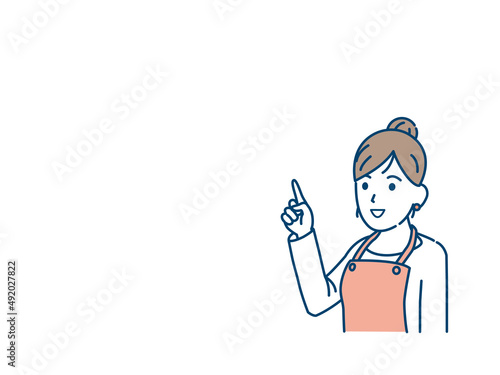 上に指をさす主婦　エプロン姿の女性　話す　説明　ポーズ　コピースペース