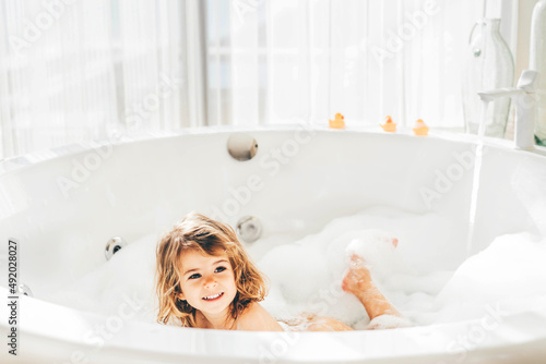 Little girl in bath playing with foam.