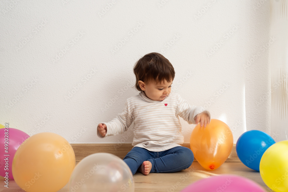 Little girl sitting on floor and playing with balloons of different colors. Little girl sitting on floor and playing with balloons of different colors.