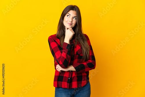 Teenager Brazilian girl isolated on yellow background thinking an idea while looking up