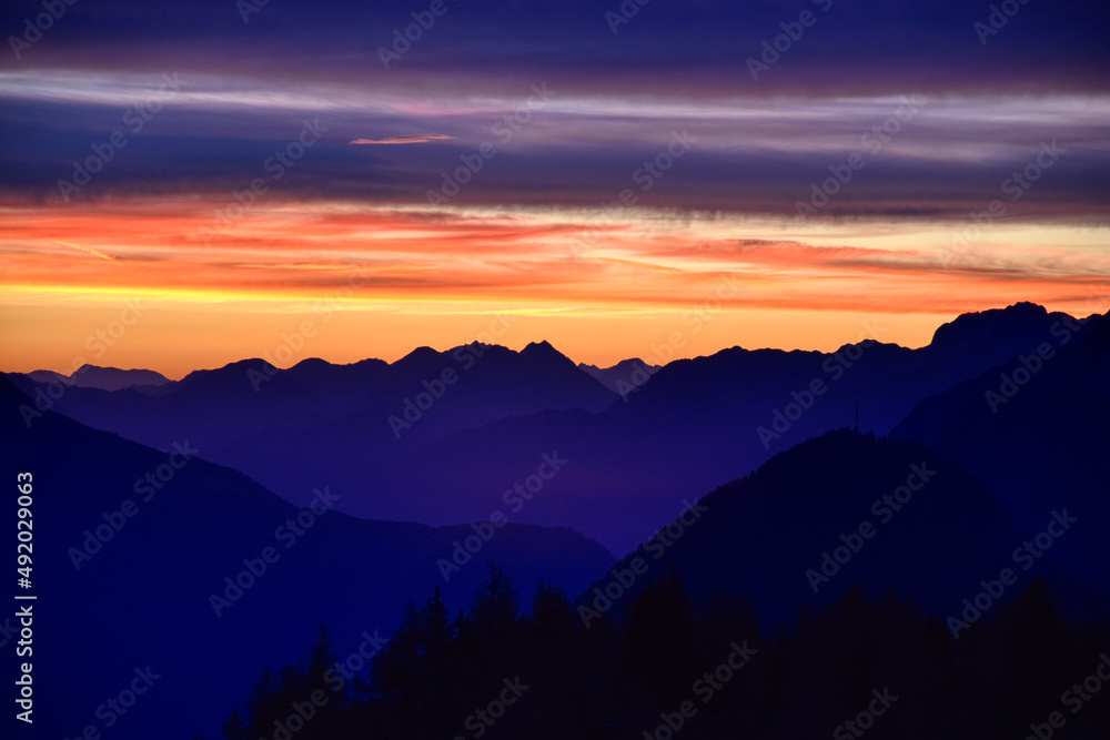 Fototapeta premium Sonnenaufgang, Morgendämmerung, Morgenrot, Himmel, Berge, Silhouette, Nacht, Tag, Dämmerung, blaue Stunde, Sonne, Sonnenstrahlen, leuchten, anleuchten, erstrahlen, Wolken, Wolkenschleier, Rot, Orange,