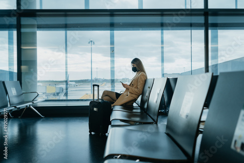 Young woman sitting at the empty airport hall. Waiting for flight. Cover photo