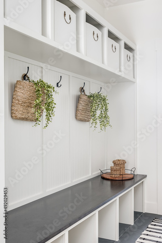 Custom built white mudroom bench and coat hangers with white storage bins. photo