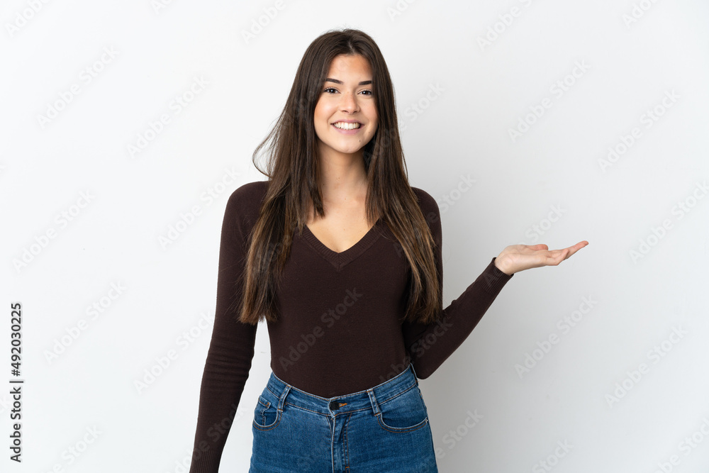 Teenager Brazilian girl isolated on white background holding copyspace imaginary on the palm to insert an ad Teenager Brazilian girl isolated on white background holding copyspace imaginary on the palm to insert an ad