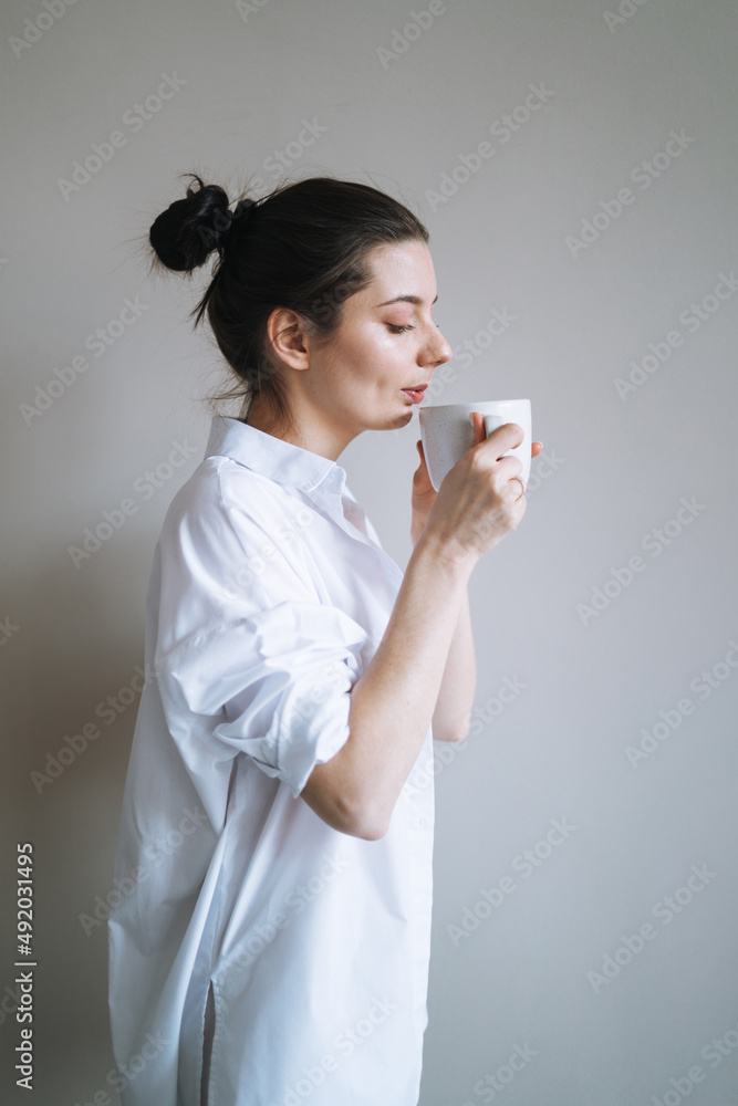 Beautiful smiling woman teenager girl student with dark long hair in home clothes with the morning cup of coffee or tea Beautiful smiling woman teenager girl student with dark long hair in home clothes with the morning cup of coffee or tea