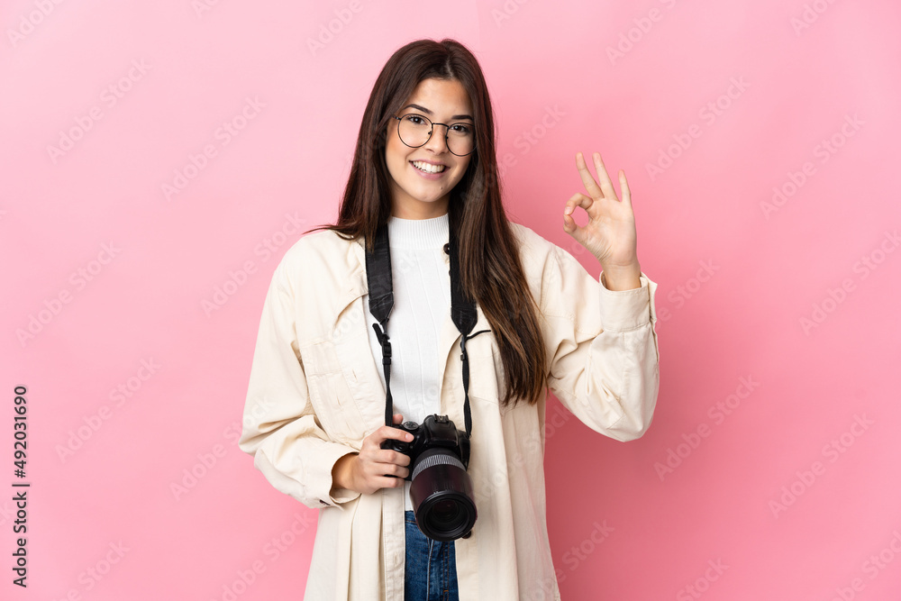 Young photographer Brazilian girl isolated on pink background showing ok sign with fingers Young photographer Brazilian girl isolated on pink background showing ok sign with fingers