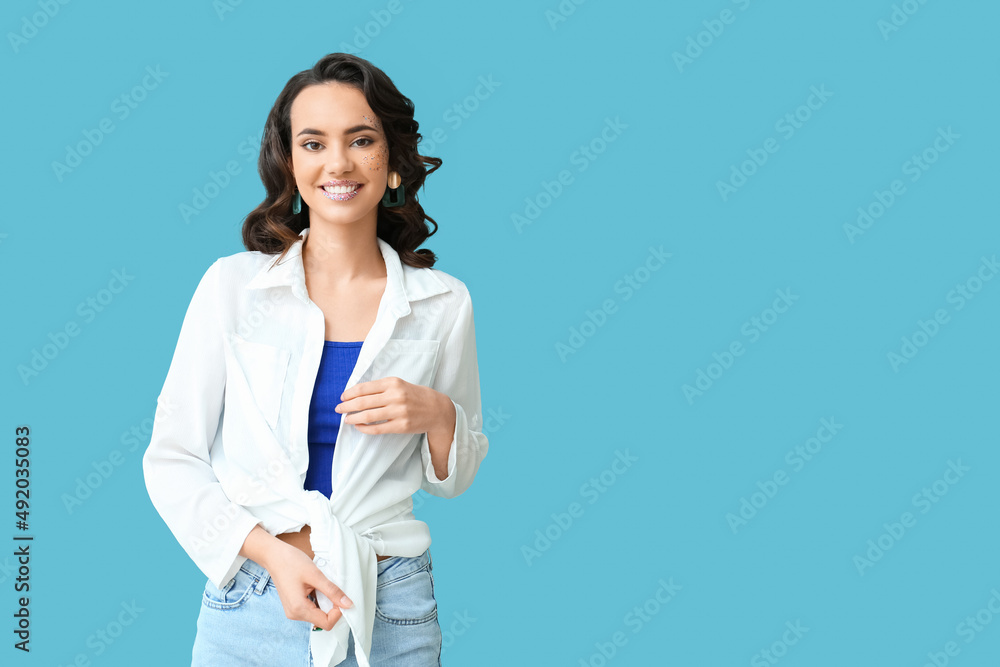 Attractive young woman with glitters on her face against blue background Attractive young woman with glitters on her face against blue background