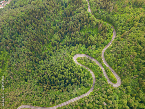 Winding road from high mountain pass, in summer time. Aerial view by drone . Romania