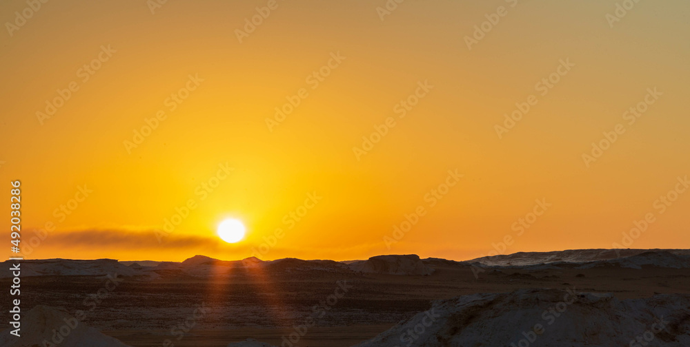 Sun going down and orange sky, wind eroded rock formations, Egyptian White Desert. Western Desert, Egypt