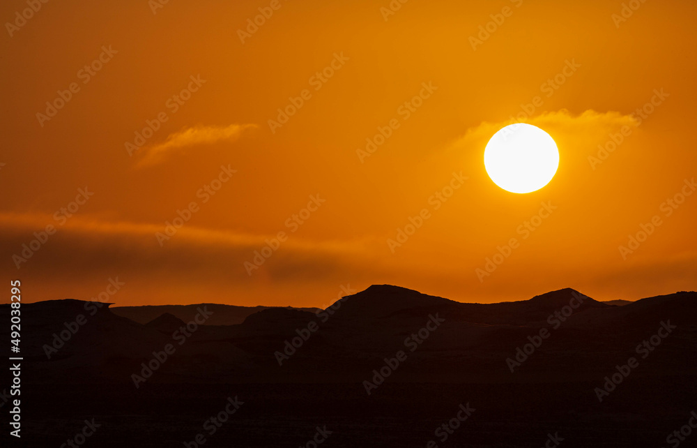 Sun and orange sky, wind eroded rock formations, Egyptian White Desert. Western Desert, Egypt Sun and orange sky, wind eroded rock formations, Egyptian White Desert. Western Desert, Egypt