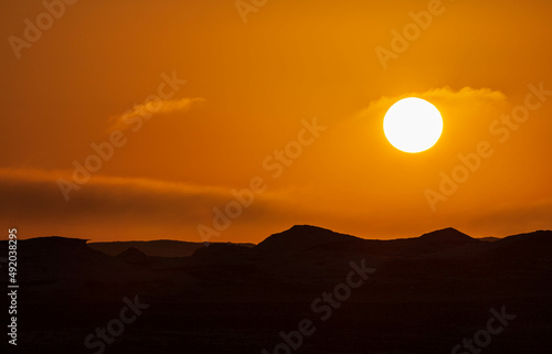 Sun and orange sky, wind eroded rock formations, Egyptian White Desert. Western Desert, Egypt
