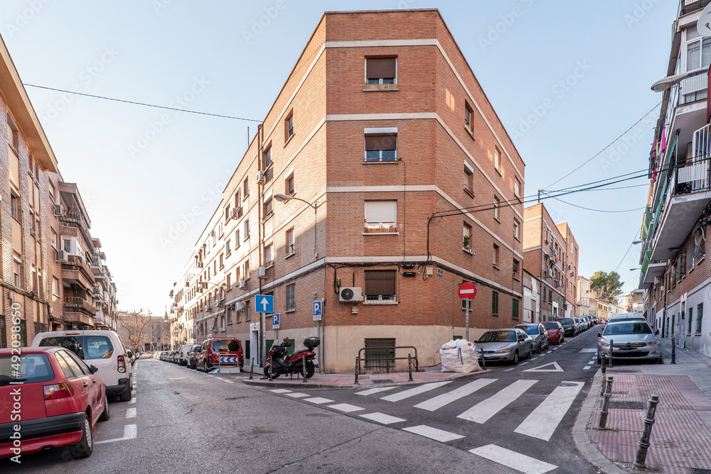 Facades of urban residential buildings with clay-colored bricks and a street intersection