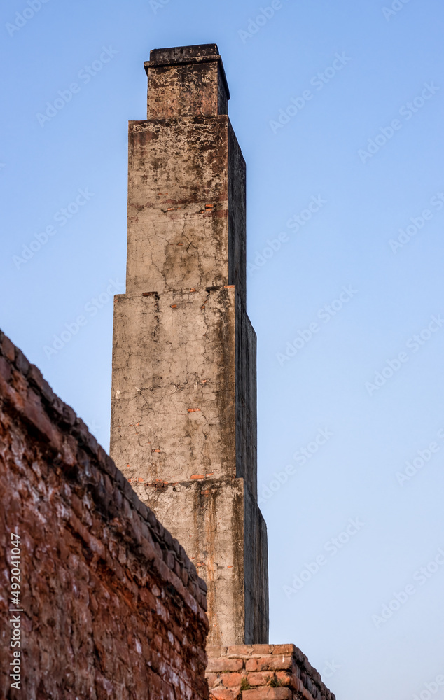 Close up bottom view of an abandoned old brick kiln  or chimney under the evening blue sky