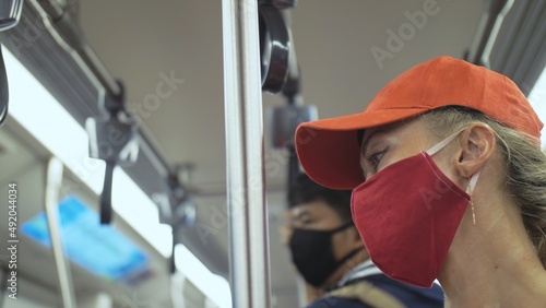 Woman travel caucasian ride at overground train airtrain with wearing protective medical red mask. Girl tourist at airtrain with respirator. Pandemic virus Coronavirus covid-19. People in mask.