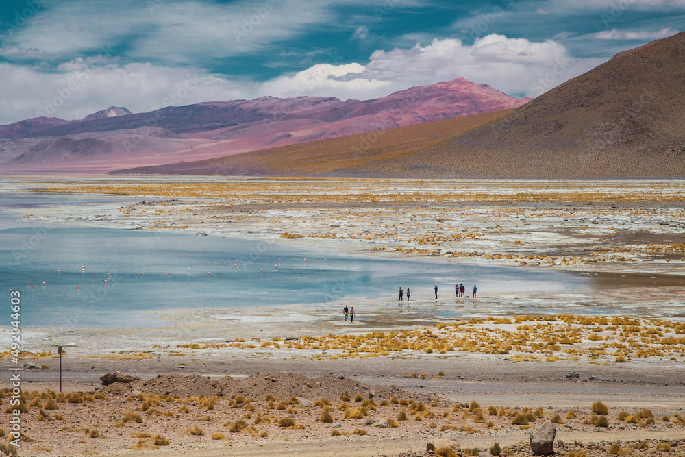 People on the shore of a lagoon in the Chalviri Salt Flat in the Bolivian highlands
