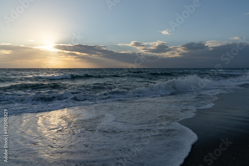 ocean sunset with waves crashing on a black sand beach