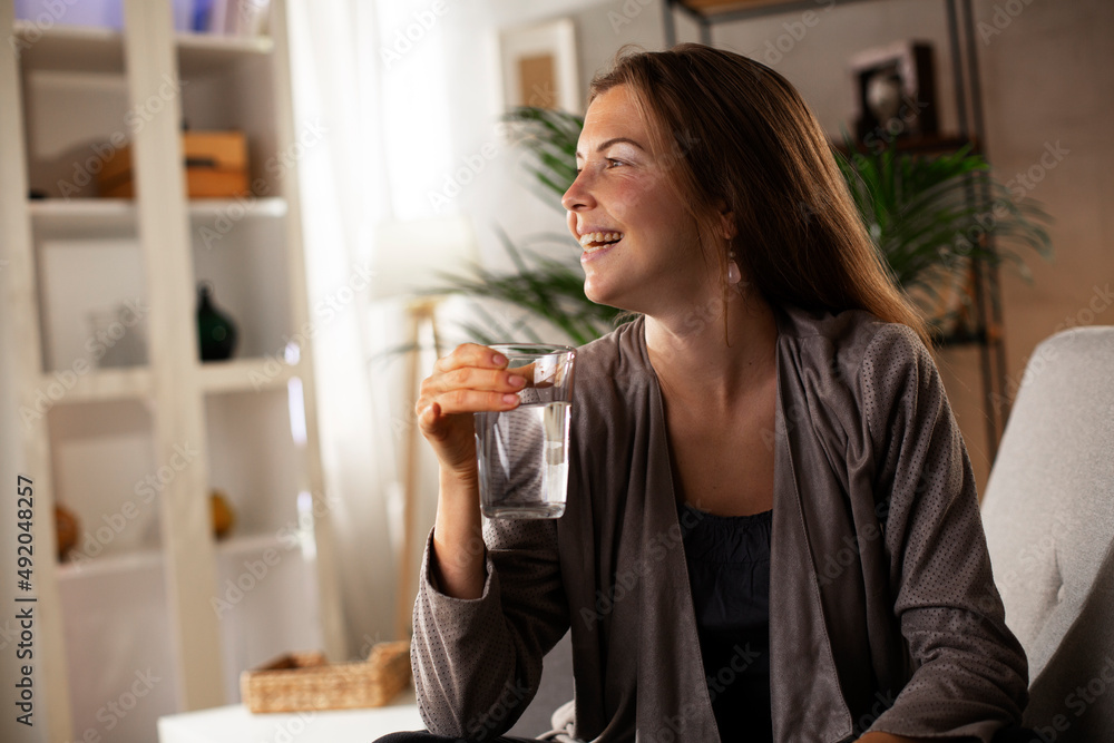 Girl holding a glass of water. Smiling girl drinking water while using the laptop. Girl holding a glass of water. Smiling girl drinking water while using the laptop.