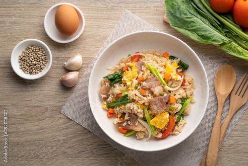 Easy Pork Fried Rice with kale, carrot, egg, onion and tomato in white plate.Top view